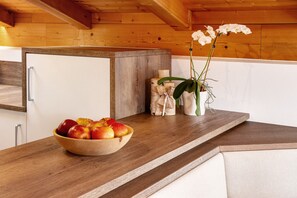 A wooden countertop with a bowl of fruit, a vase with flowers, and a small wooden cabinet. - Apartment 'Zeppenhof' with Mountain View, Private Terrace and Wi-Fi (Santa Valburga St. Walburg)