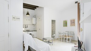 A clinical room with a bed, a small table, chairs, a desk with a computer, and a wall-mounted shelf. - Apartment 'Sevilla Centro Con Piscina' with Shared Pool, Wi-Fi and Air Conditioning (Sevilla)