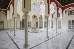 A spacious courtyard with marble flooring, white columns, and arched doorways. - Apartment 'Sevilla Centro Con Piscina' with Shared Pool, Wi-Fi and Air Conditioning (Sevilla)