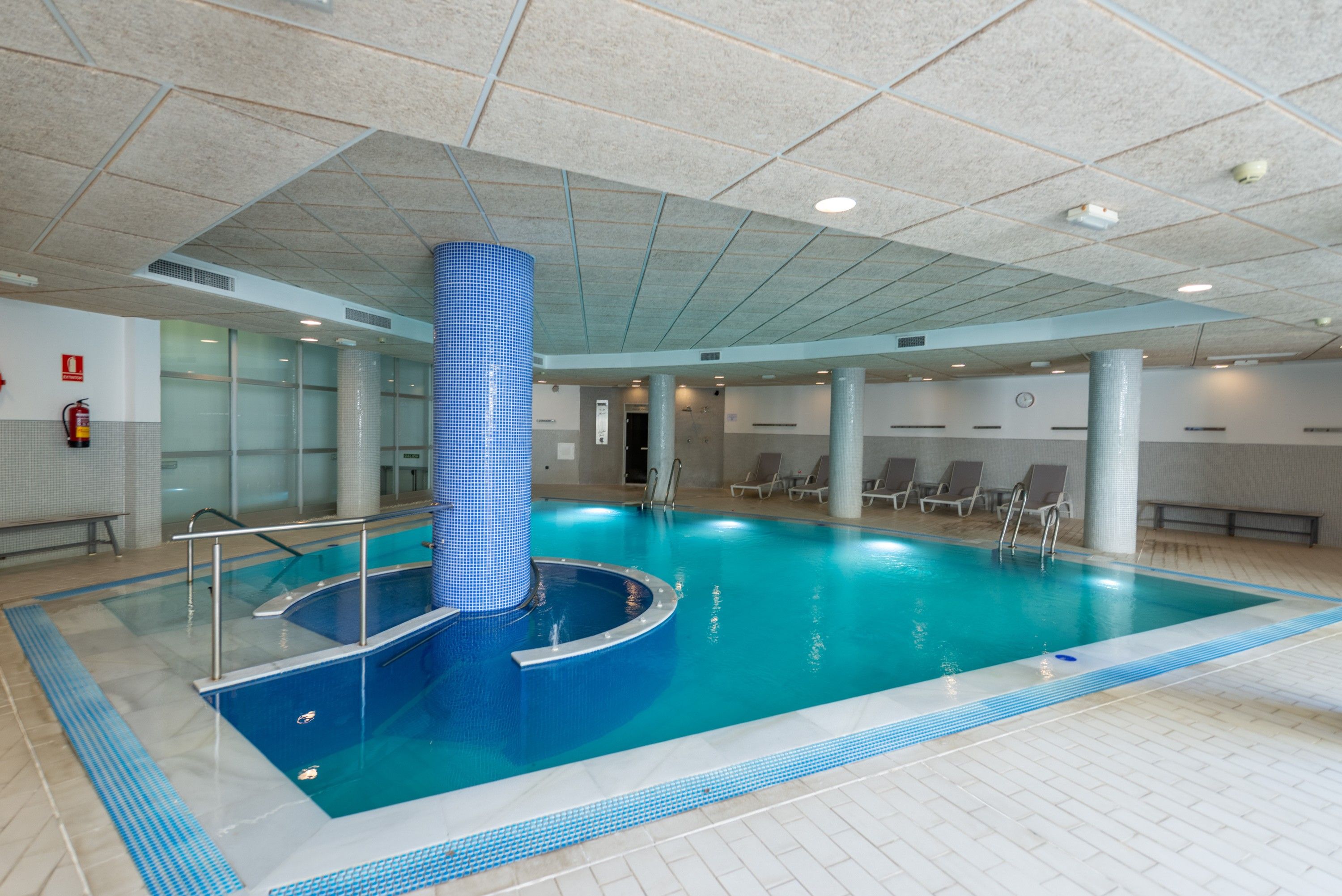 Ein Innenpool mit einer blauen Säule aus Fliesen, klarem Wasser und einem gefliesten Boden.