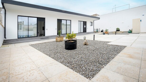 A modern building with large windows, a flat roof, and a gravel courtyard with potted plants. - Holiday Home 'Tre' with Shared Terrace, Wi-Fi and Air Conditioning (Melendugno)