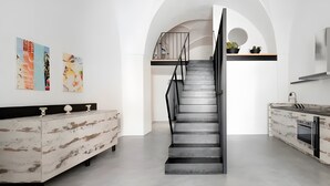 A modern kitchen with a central staircase, white walls, and minimalist decor. - Holiday Home 'Tre' with Shared Terrace, Wi-Fi and Air Conditioning (Melendugno)