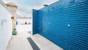 Une zone de douche aux carreaux bleus, dotée d’un drain, un objet décoratif vert et un mur blanc.