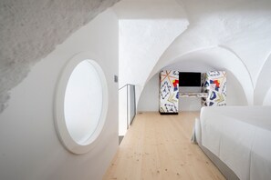 Un dormitorio con un tragaluz circular, una cama, un televisor y un armario con diseño.