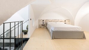 Un dormitorio con techo inclinado, una cama, una escalera y una planta en maceta.