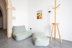 Habitación minimalista con un sofá verde, un caballete de madera y un cuadro colgado en la pared.