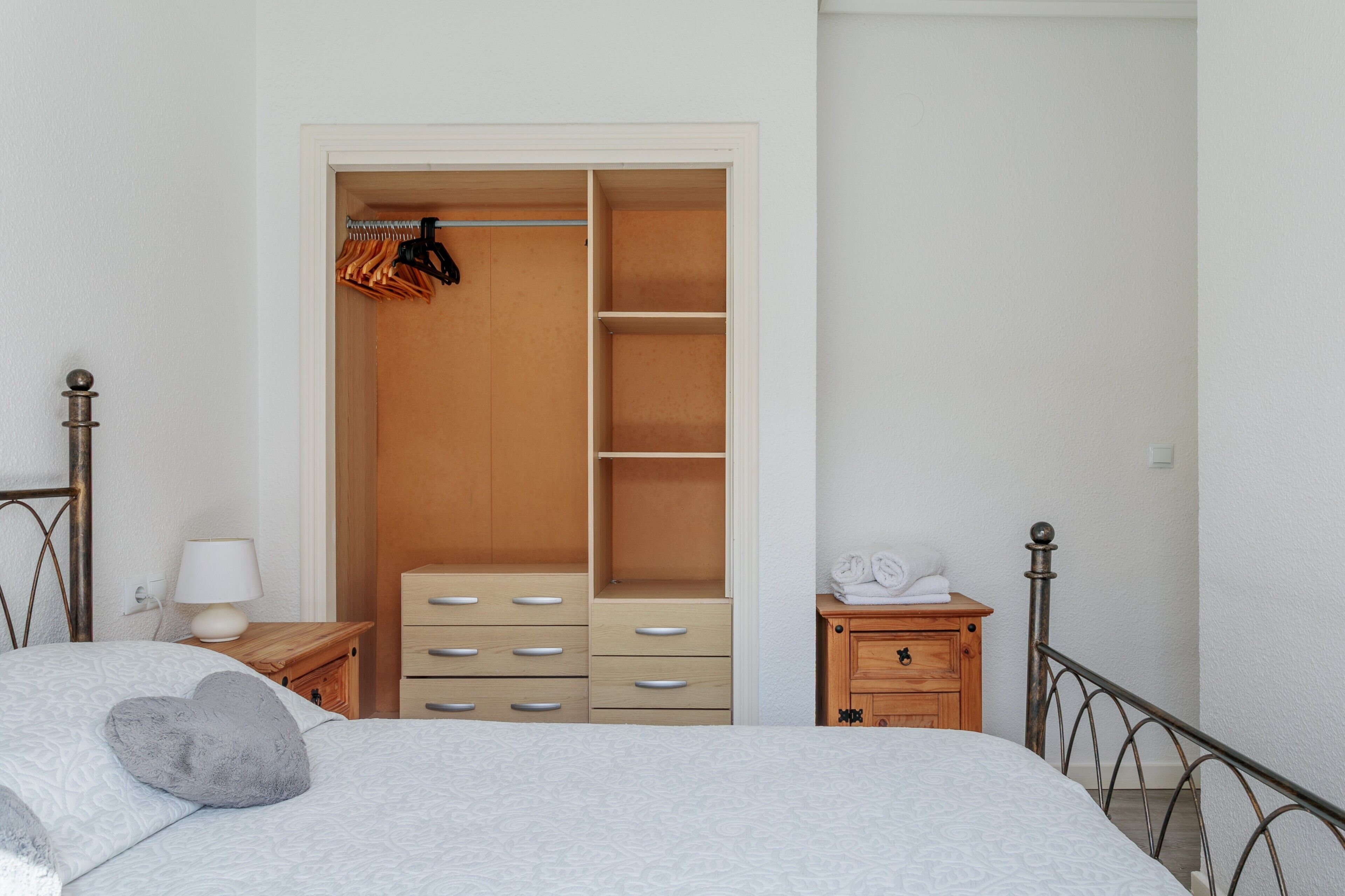 Una camera da letto con un letto, un armadio in legno, un comodino con una lampada e un piccolo mobiletto con asciugamani.