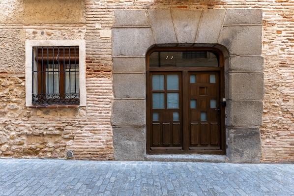 A stone building with a wooden door and a window with metal bars.
