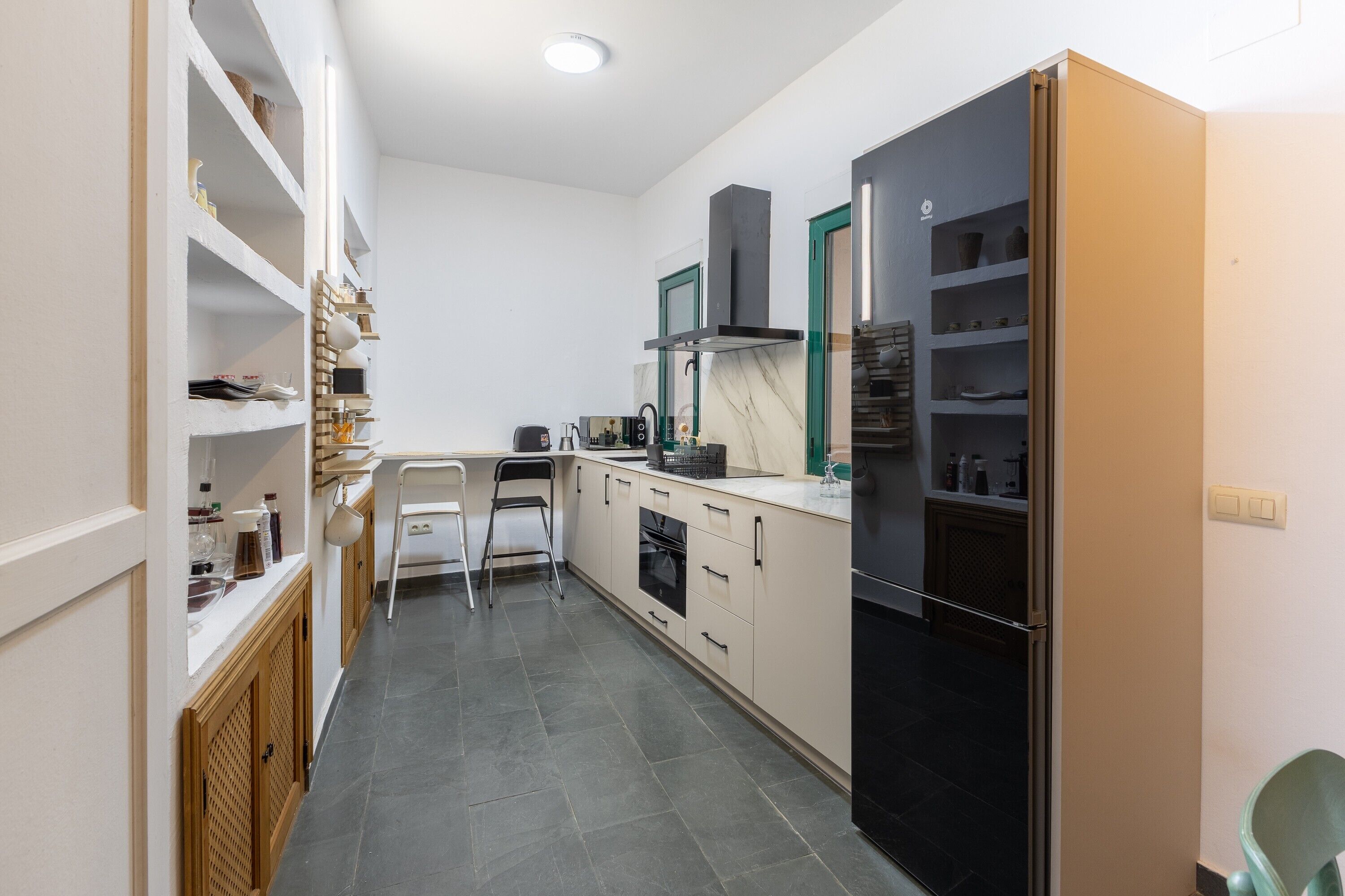 A compact kitchen with a built-in oven, a black refrigerator, and a white countertop.