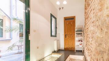 A hallway with a wooden door, a radiator, a small table, and a shelf with items.