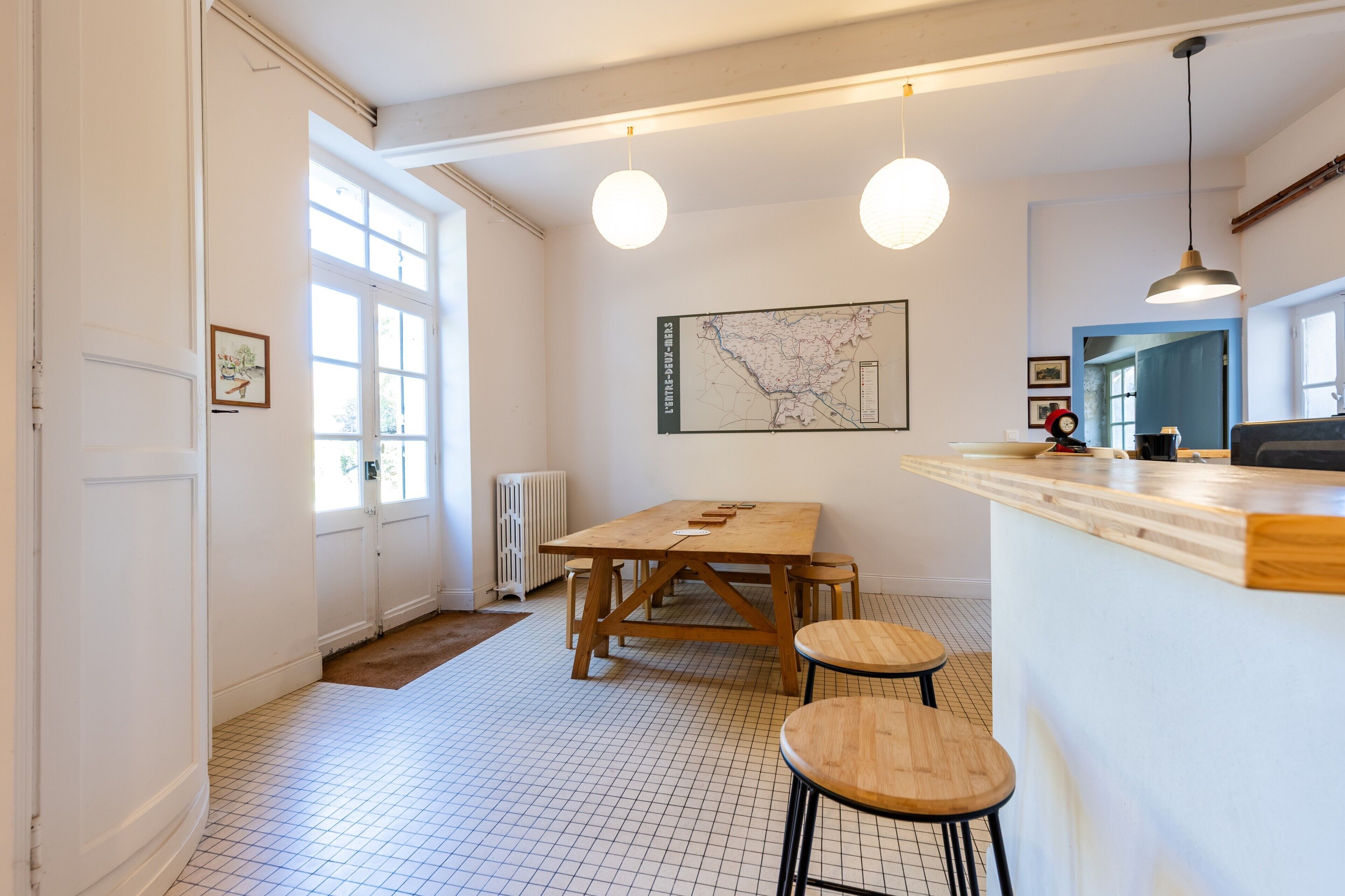Cozinha moderna com mesa de madeira, banquetas, luminárias pendentes e um mapa na parede.