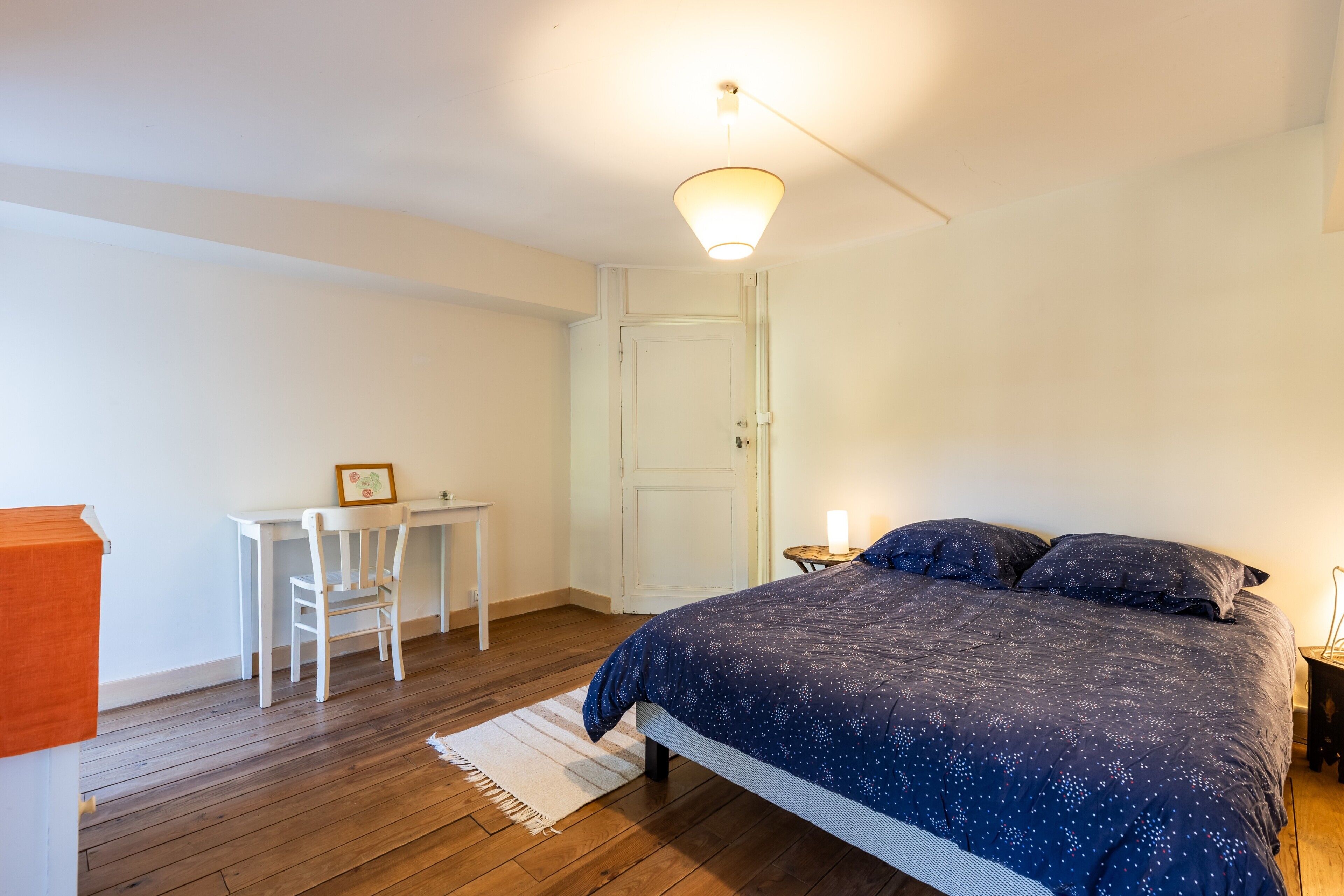 A bedroom with a bed, a desk, and a chair.