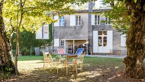 A house with a garden, outdoor seating, and a staircase leading to the entrance.