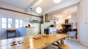 A spacious kitchen with a long wooden table, a built-in stove, and a dining area with chairs.
