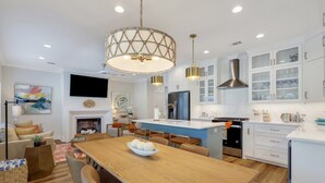 A modern kitchen with white cabinets, a central island, and a dining area with a wooden table and chairs.