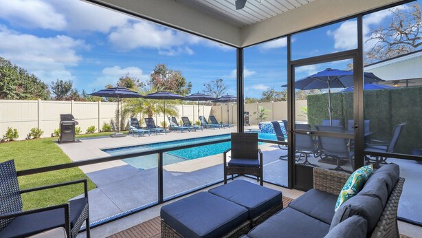A covered outdoor area with a pool, lounge chairs, and umbrellas.