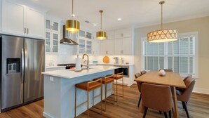 A modern kitchen with white cabinets, stainless steel appliances, and a central island with bar stools.