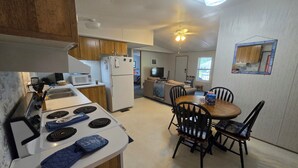 A compact kitchen with a stove, microwave, and refrigerator. There is a dining area with a table and chairs. - Entire 3-bedroom 2-bath home that is only 2.5 miles from Sunset Beach ocean. (Sunset Beach)