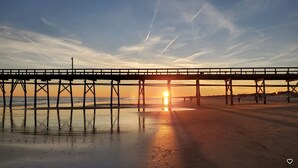 A pier extending over a beach with the sun setting in the background. - Entire 3-bedroom 2-bath home that is only 2.5 miles from Sunset Beach ocean. (Sunset Beach)