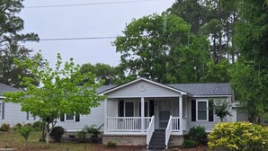 A single-story house with a front porch and a staircase leading to the entrance. - Entire 3-bedroom 2-bath home that is only 2.5 miles from Sunset Beach ocean. (Sunset Beach)