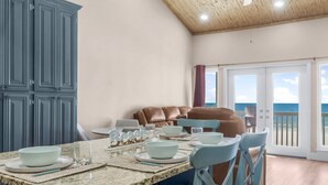 A kitchen with a granite countertop, white bowls, and glasses. There is a brown leather sofa and a dining table with chairs. - Beachfront - West End PCB - Gulf Views (Panama City Beach)