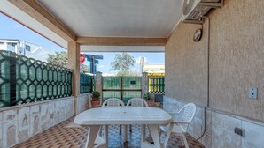 Terrassa a l'aire lliure amb sòl de rajola, taula blanca i dues cadires blanques.