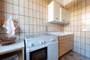Une cuisine équipée d’une cuisinière, d’un four, d’un évier et de placards.