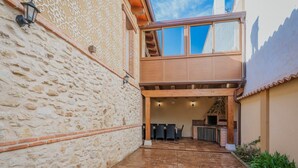 A courtyard with stone walls, a wooden deck, a seating area, and a brick fireplace.