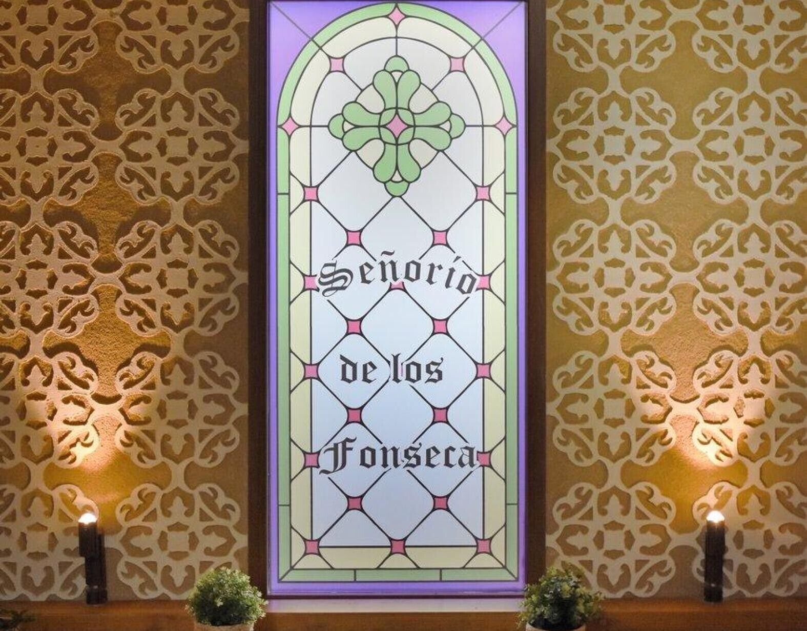 Un vitral con la inscripción 'Senorio de los Fonseta' y motivos decorativos en la pared.