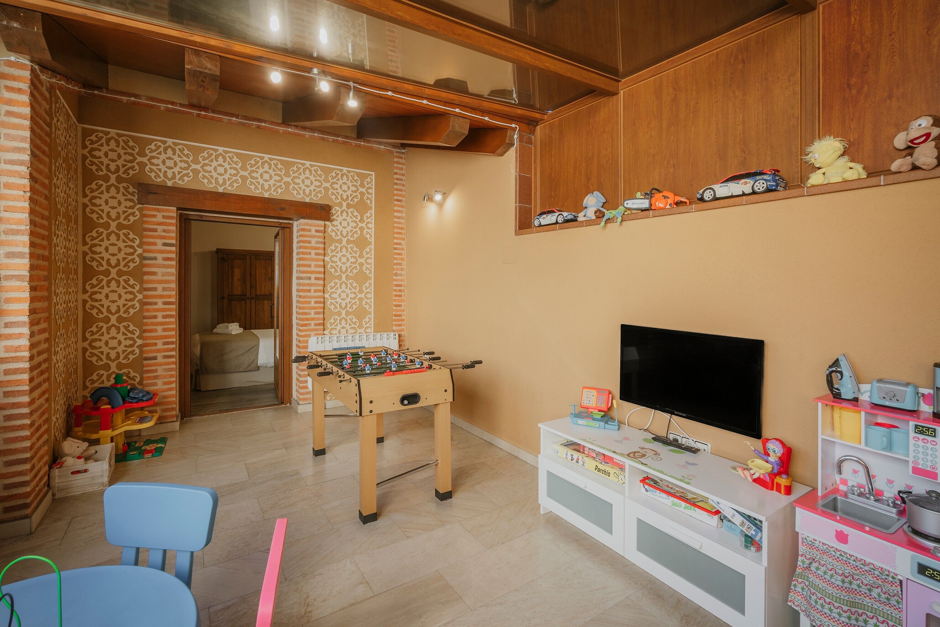 Une pièce avec un baby-foot, une télévision et une étagère remplie de jouets.