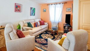 A living room with a sofa, armchairs, a TV, and a patterned rug.