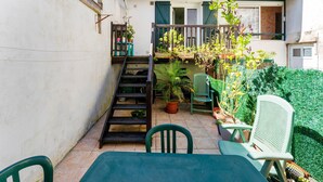 A patio with a table and chairs, a staircase, and potted plants.