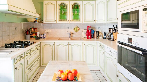A kitchen with white cabinets, a Bosch microwave, and a sink.