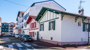A street with buildings, parked cars, and a clear sky.