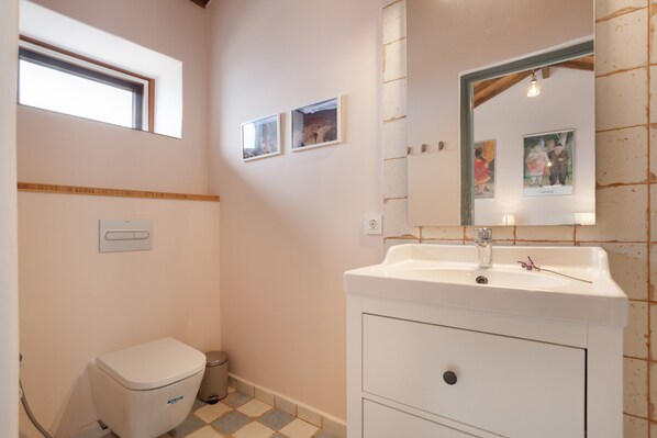 A bathroom with a toilet, sink, mirror, and two framed pictures on the wall. - 'Casa Del Cielo' with Sea View, Private Pool and Wi-Fi (Adeje)