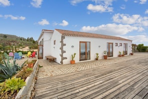 A white building with a tiled roof, wooden deck, and potted cacti. - 'Casa Del Cielo' with Sea View, Private Pool and Wi-Fi (Adeje)