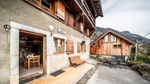 Un chalet en bois doté d’un coin repas, d’un banc et offrant une vue sur les montagnes.