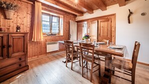Un intérieur en bois comprenant une table à manger, des chaises, un buffet et une fenêtre avec des rideaux.