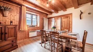 Un intérieur en bois comprenant une table à manger, des chaises, un buffet et une fenêtre avec des rideaux.