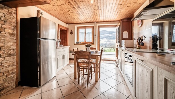 Une cuisine avec un plafond en bois, un mur en pierre et une vue sur un paysage enneigé.