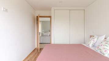 Een slaapkamer met een bed, een kledingkast en een badkamer die door een open deur zichtbaar is.