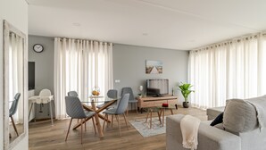 Una sala moderna con comedor, televisor y sofá.