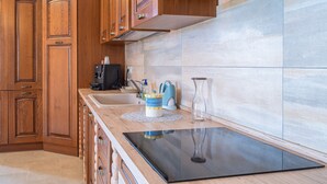 Una cocina con armarios de madera, una encimera negra, una cafetera y un florero.