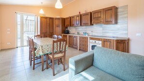 Una cocina moderna con armarios de madera, una mesa de comedor con sillas y un sofá en una sala de estar luminosa.