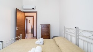 Un dormitorio con cama, cómoda de madera, armario y una puerta que da a otra habitación.