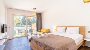 Ein Hotelzimmer mit einem großen Bett, einem Fernseher, einem Balkon mit Sitzgelegenheit und einer Schiebetür.