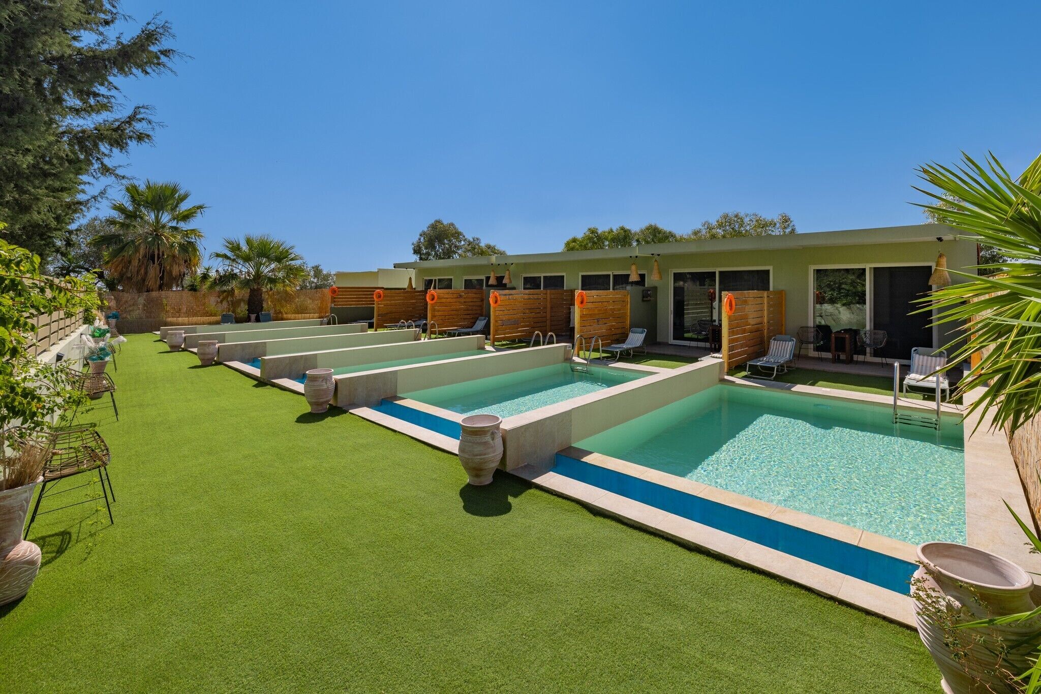 A pool area with multiple pools, lounge chairs, and a building with large windows.