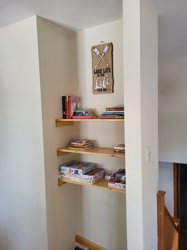 Un coin d’une pièce avec une bibliothèque en bois contenant des livres et des jeux de société.
