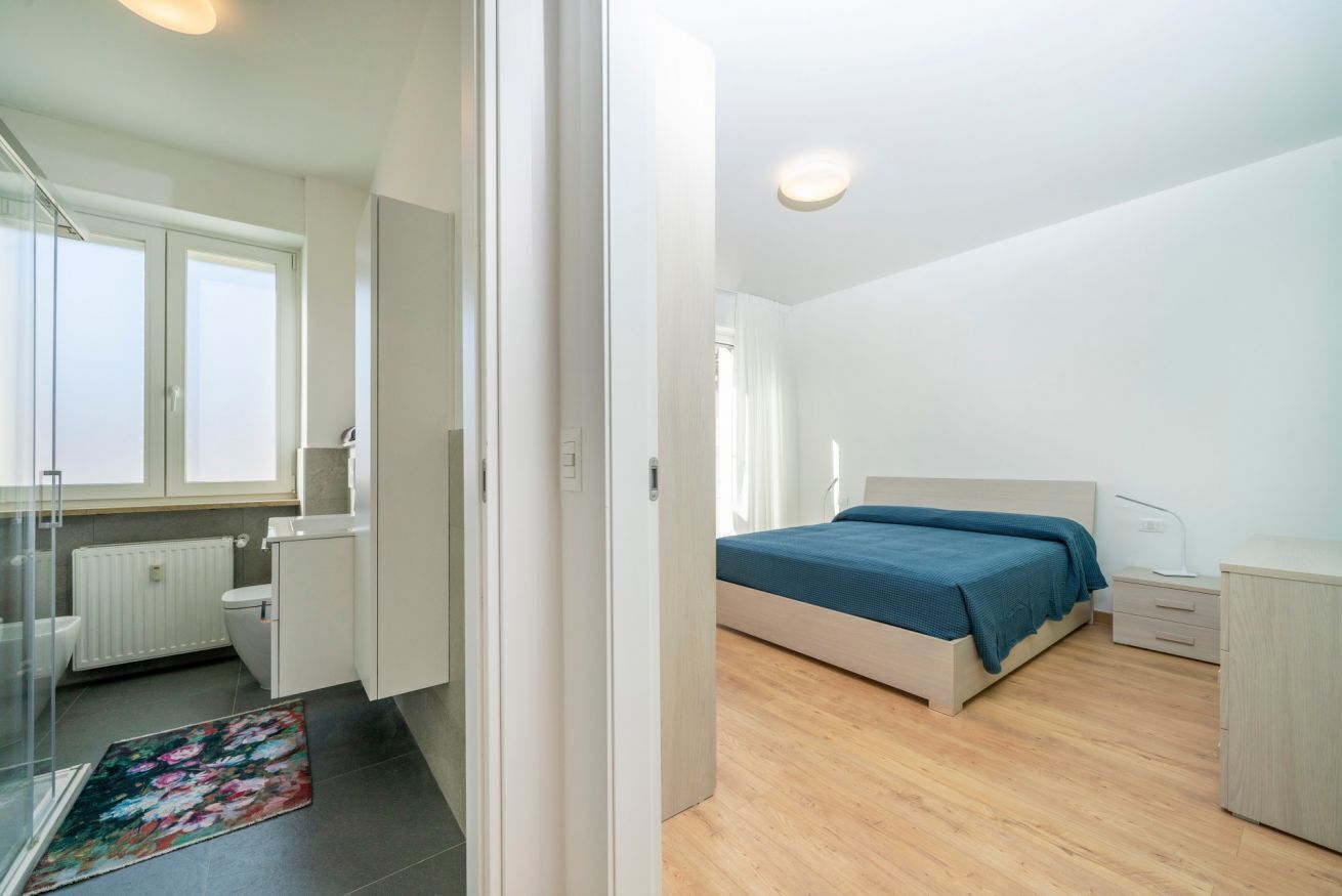 Ein Schlafzimmer mit Bett, Nachttisch und Blick ins Badezimmer.