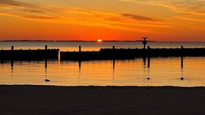 A sunset over a calm body of water with a pier extending into the water. - 3 bedroom, waterfront cottage on the shores of the Chesapeake Bay. (North Beach)